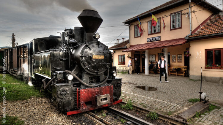 Eine Dampflok fährt mit einem Waggon auf den Gleisen in Rumänien